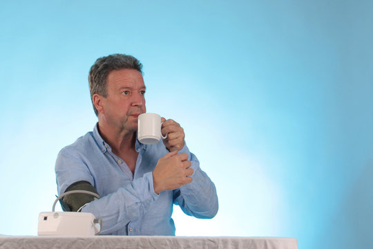 Ein Mann beim Blutdruck messen und Tee trinken