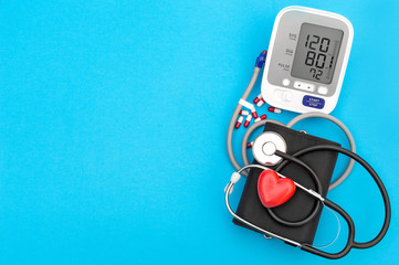 Blood pressure tonometer with red heart and stethoscope on blue background. Medical concept. Top...