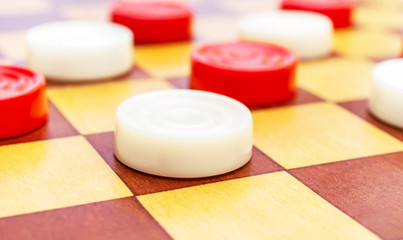 Checkers on wooden checkerboard. Close up.