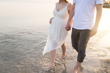 Couple holding hands walking romantic on beach on vacation travel holidays. Closeup of body and golden sand for copy space. Young loving couple