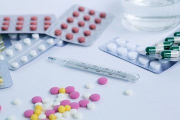pills and thermometer on white background