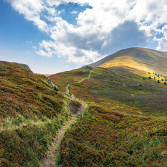 trail uphill through the mountain ridge to the top. sunny august weather with clouds on the blue...