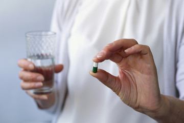 woman's hand with pills and glass of water