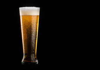 Glass of beer with foam on black background