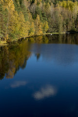 Beautiful reflections on the forest pond partly covered with thin ice in Nuuksio National Park, Finland