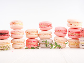 Colorful French or Italian macarons stack on white wood table with copy space for background. Dessert for served with afternoon tea or coffee break