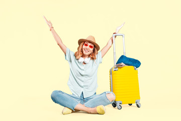 Happy asian woman traveler with suitcase on color background in studio. Vacation and tourist trip concept.