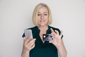 Photo of smiling adult lady with mobile and credit card in her hands