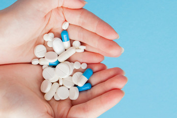 Woman's holding cupped hand full of pills, view from above