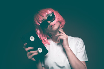 Young girl 90s and VHS cassette on pink background.