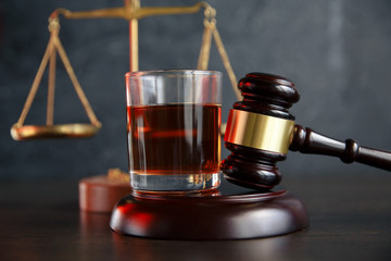 The concept of a DUI. Law hammer, alcohol and car keys on wooden table, dark background