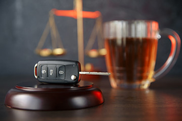 The concept of a DUI. Law hammer, alcohol and car keys on wooden table, dark background