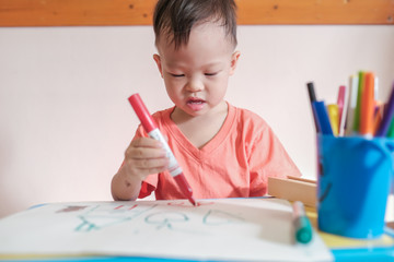 Cute little Asian 2 - 3 years old young toddler boy child drawing, scribbling with pen color...