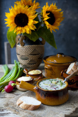 Summer cold soup with vegetables On a wooden table with a bouquet of sunflowers.