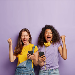 Optimistic mixed race female classmates clench fists from joy, receive confirmation of entering...