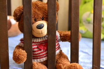 teddybear is sitting in the crib, a photo on the children's theme, in the children's bedroom, interior design, cute fluffy bear.