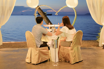 Young couple enjoying a romantic dinner by candlelight, outdoor.  Romantic meal on the beach with...