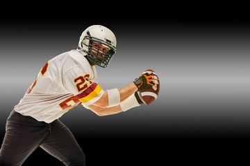 American football player in motion with the ball on a black background with a light line, copy space. The concept of the game is American football, movement.