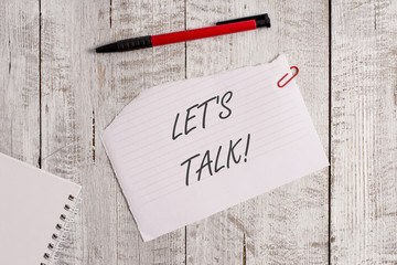 Word writing text Let S Is Talk. Business photo showcasing suggesting in the beginning of a conversation on the topic Torn paper and notebook sheet with a pen placed on top of wooden table