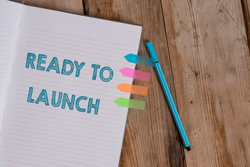 Conceptual hand writing showing Ready To Launch. Concept meaning an event to celebrate or introduce something new to market Striped notebook colored arrow banners ballpoint wooden background