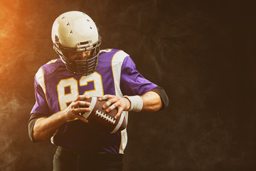 Portrait close-up, American football player, bearded without a helmet with the ball in his hands. The concept of American football, sports anger, close-up, special illumination, the effect of film