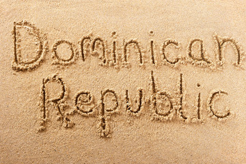 Dominican Republic word written in sand sign writing drawing drawn on a sunny summer beach holiday...