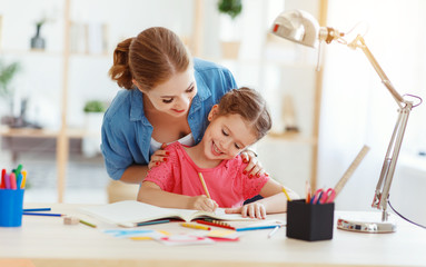 mother and child daughter doing homework writing and reading at home.