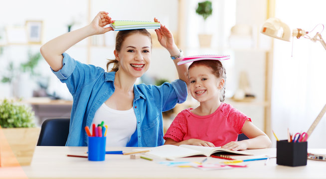 funny mother and child daughter doing homework writing and reading