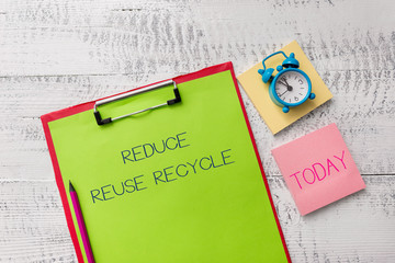 Handwriting text Reduce Reuse Recycle. Conceptual photo environmentallyresponsible consumer behavior Metal clipboard sheets marker alarm clock notes pad wooden background
