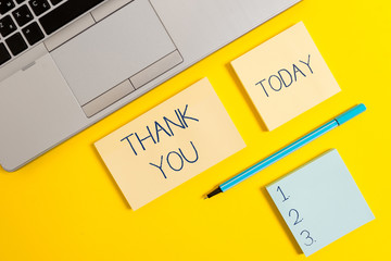 Conceptual hand writing showing Thank You. Concept meaning a polite expression used when acknowledging a gift or service Silver laptop square sticky notepads marker colored background