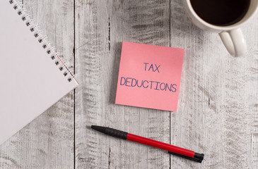 Handwriting text Tax Deductions. Conceptual photo an amount or cost that subtracted from someone s is income Stationary placed next to a cup of black coffee above the wooden table