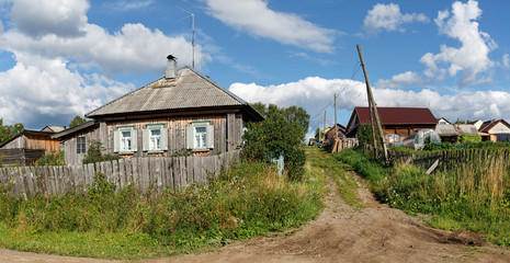 Panoramic view of the village street with old and new wooden houses. Village of Visim, Sverdlovsk region, Russia.