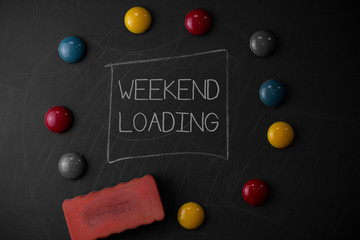 Text sign showing Weekend Loading. Business photo text Starting Friday party relax happy time resting Vacations Round Flat shape stones with one eraser stick to old chalk black board