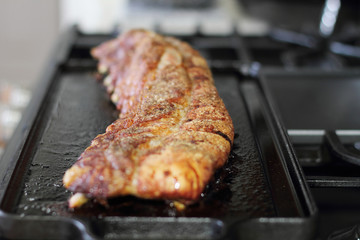 Rack of dry rub pork ribs baked on a cast iron tray, resting on the stove top.