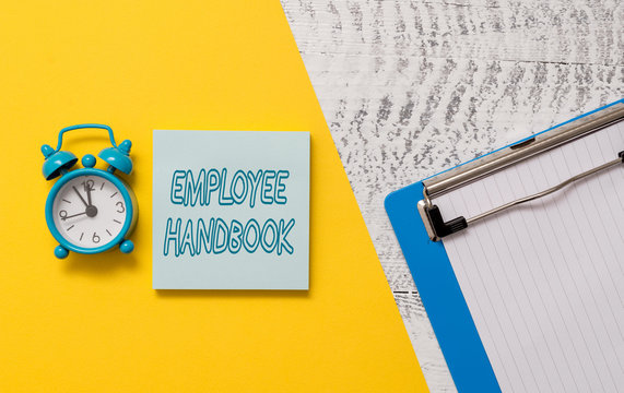 Conceptual hand writing showing Employee Handbook. Concept meaning Document that contains an operating procedures of company Notepad colored paper sheet alarm clock wooden background