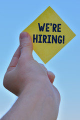 Handwriting text writing We Re Hiring. Conceptual photo process of reviewing applications and finding candidates Piece of square paper use to give notation hold by one hand raising up