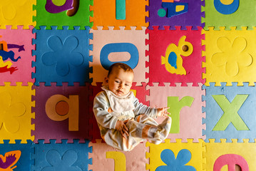 Baby in pajamas doing yoga lying on the floor to develop.