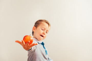 Happy boy showing his lunch, an apple he holds in his hand, healthy fruit to grow.