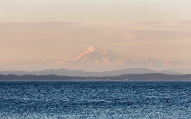 Scenic Landscape View of Distant Mount Baker near Seattle, Washington USA seen through haze during Sunset from Oak Bay on Vancouver Island, BC Canada