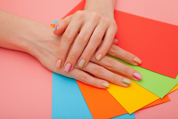 Fototapeta premium Modern stylish manicure rainbow or summer mood, on a pink table with color envelopes. Close-up