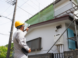 住宅とヘルメットの男性　現地調査　指差し