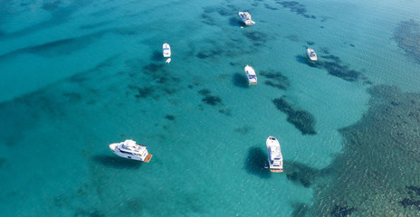 Fototapeta na wymiar View from above, stunning aerial view of some boats and yachts on a beautiful turquoise clear water. Spiaggia La Pelosa (Pelosa beach) Stintino, Sardinia, Italy.