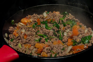 Obraz na płótnie Canvas Cast iron skillet cooking ground beef pasta sauce mixture