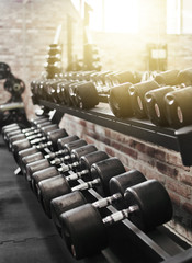 Fototapeta na wymiar Set of black dumbbell with metal handles on a rack in the gym. Free weights training, bodybuilding