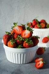 fresh natural homemade strawberries in a plate on a grey background. Hard light and shadows. organic, tasty, healthy food. Vertical orientation, copy space