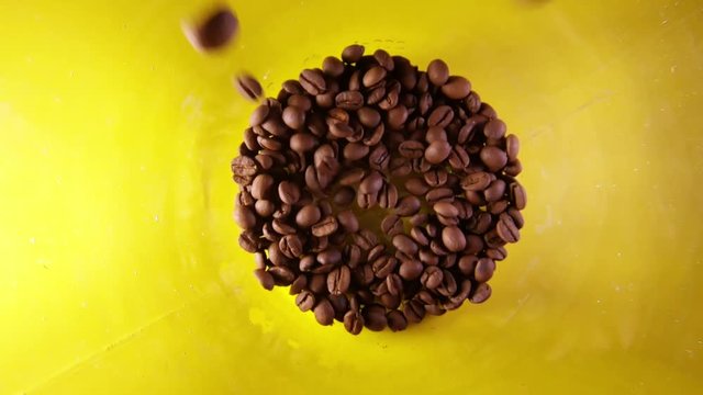 Slow Motion Of Pouring Coffee Beans Into A Glass Isolated On Yellow Bacground.