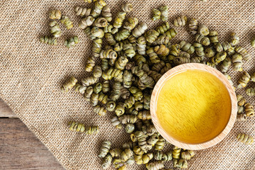 dried Shi Hu, Dendrobium huoshanense, Chineses herbal medicine on guny sack cloth with tea in wooden bowl, top view
