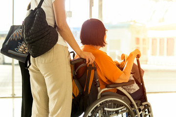 Woman with mother in wheelchair waiting for boarding at International airport.