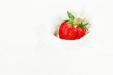 Red natural ripe strawberries falling into milk cream (
