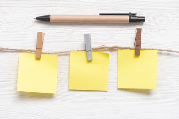 Blank paper stickers with copy space on a clothespin on a rope and a pen on a white table...